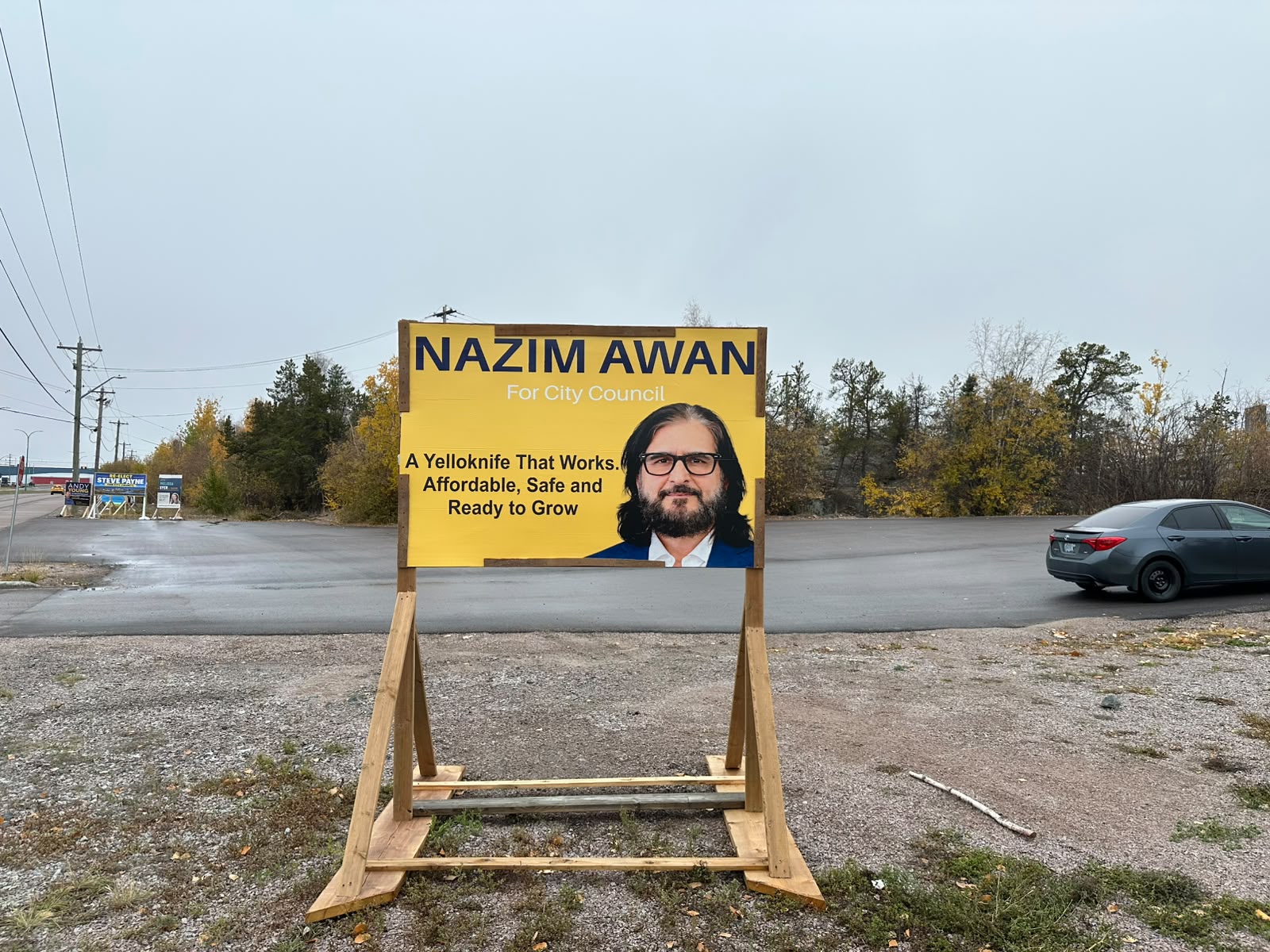 Nazim Awan campaign sign standing beside a Yellowknife street on an autumn day