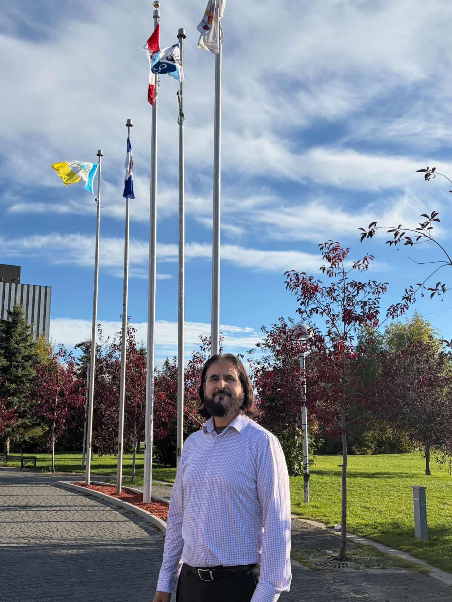 Nazim Awan standing near the flags outside Yellowknife City Hall
