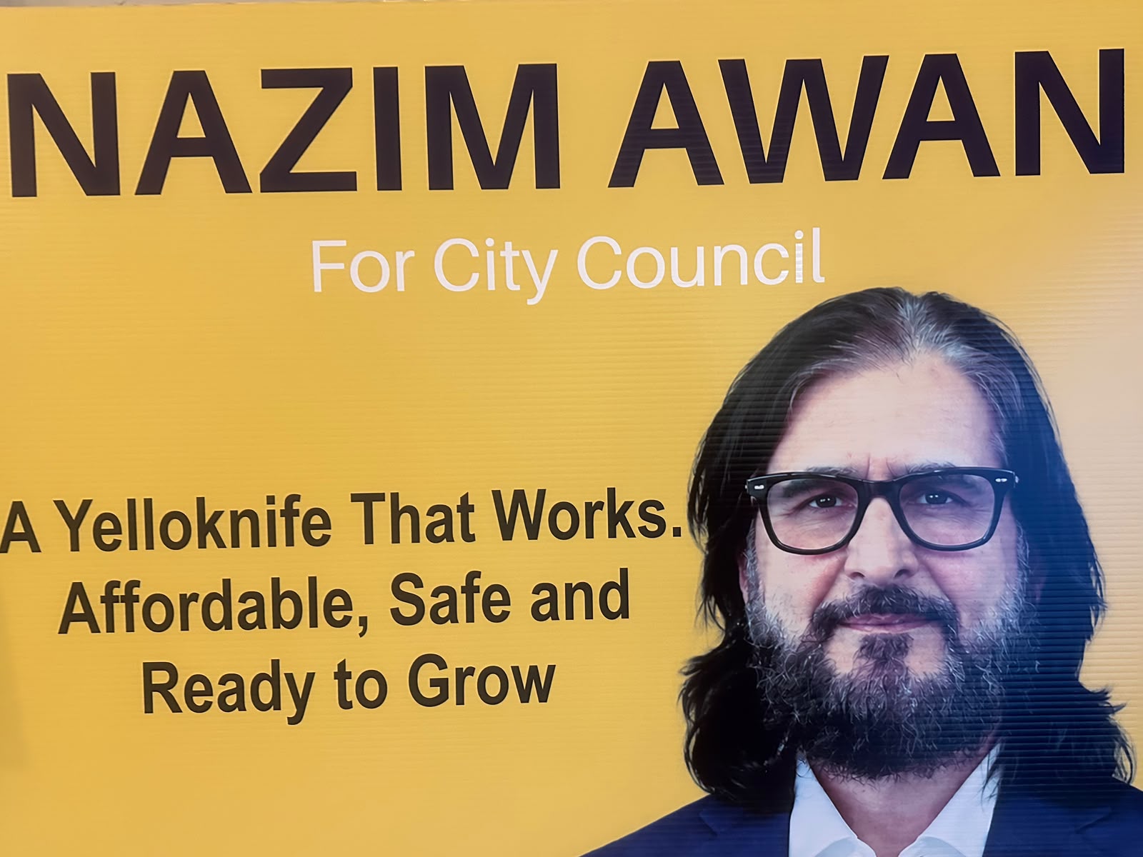 Close-up of the yellow Nazim Awan for City Council campaign sign